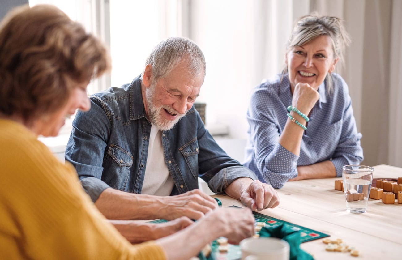 Happy senior friends playing board games and enjoying retirement